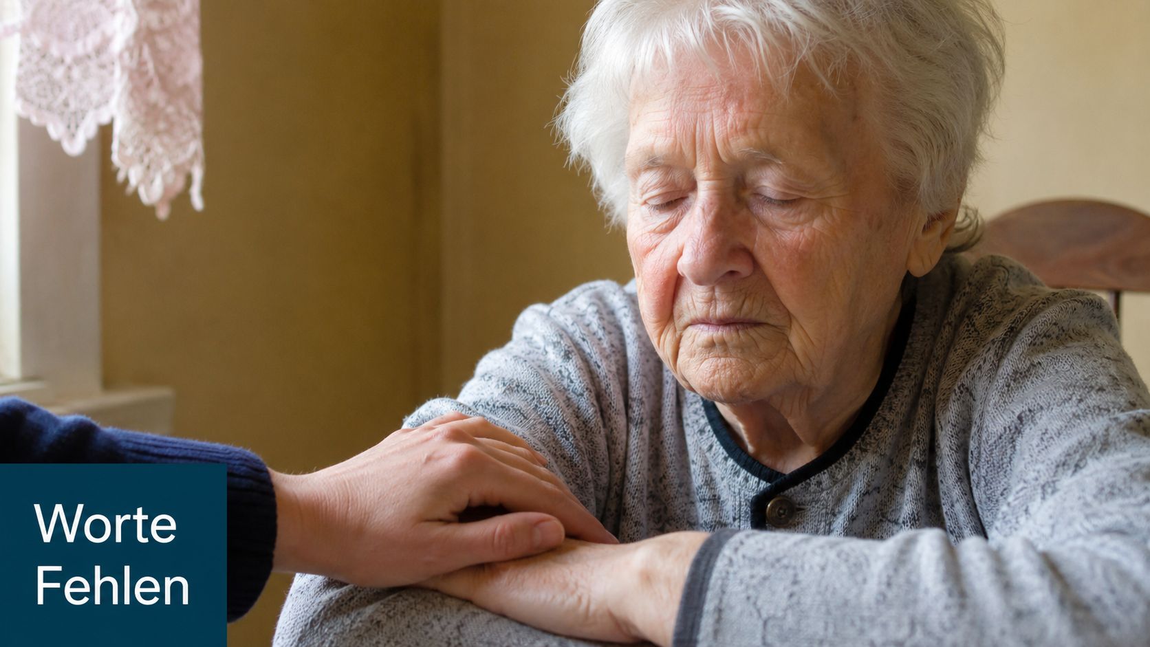 Eine liebevolle Hand berührt sanft die Hand einer betagten Frau, die mit geschlossenen Augen traurig wirkt.