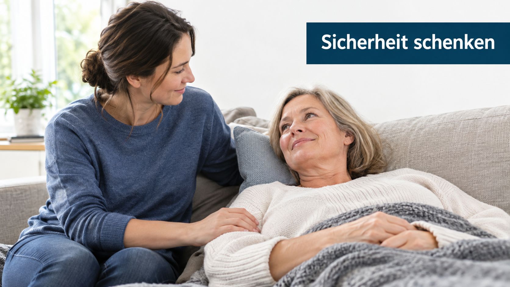 Eine junge Frau kümmert sich liebevoll um eine ältere Frau, die gemütlich auf einem Sofa entspannt liegt.